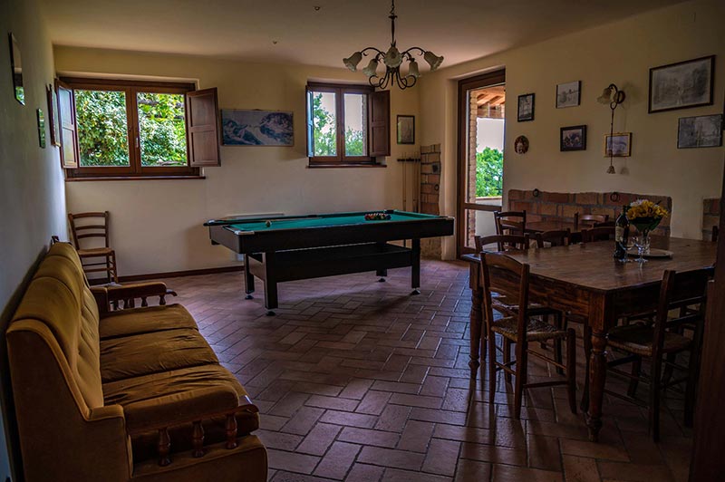 salone della casa vacanze Villa La Pieve con divano, biliardo e tavolo in legno
